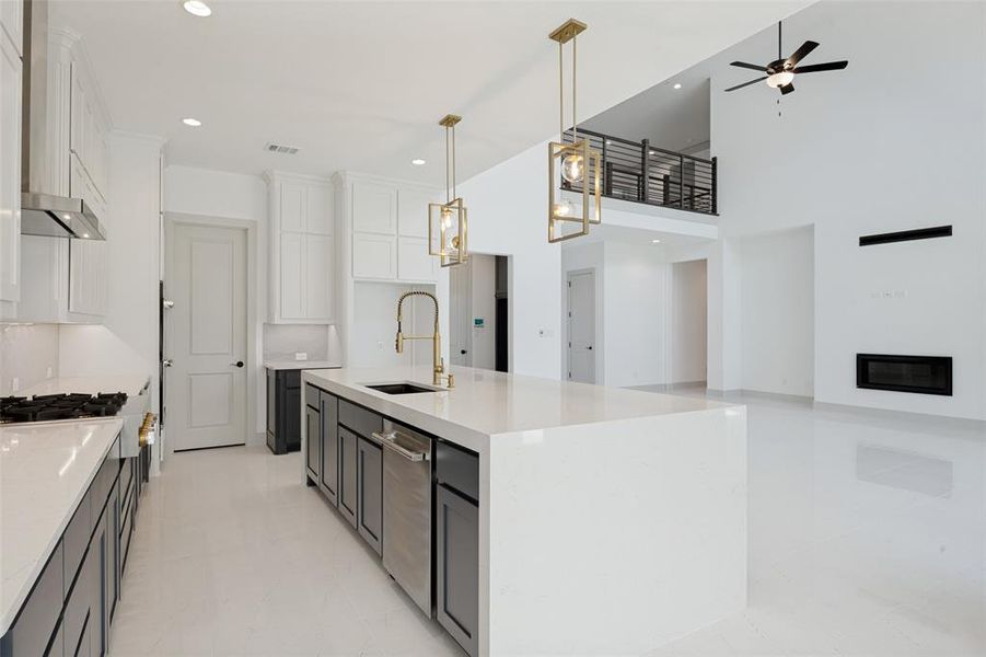 Open-concept kitchen and living area featuring a large center island with integrated sink, stainless steel appliances, recessed lighting, and modern pendant fixtures Open-concept kitchen and living area featuring a large center island with integrated sink, stainless steel appliances, recessed lighting, and modern pendant fixtures