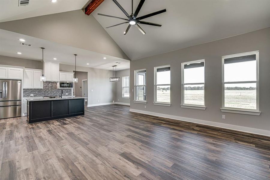 Kitchen with dark hardwood / wood-style floors, a center island with sink, hanging light fixtures, appliances with stainless steel finishes, and white cabinetry