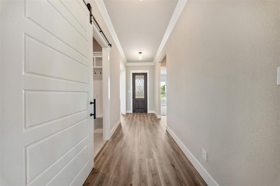 Entryway with a barn door, crown molding, and wood finished floors Entryway with a barn door, crown molding, and wood finished floors