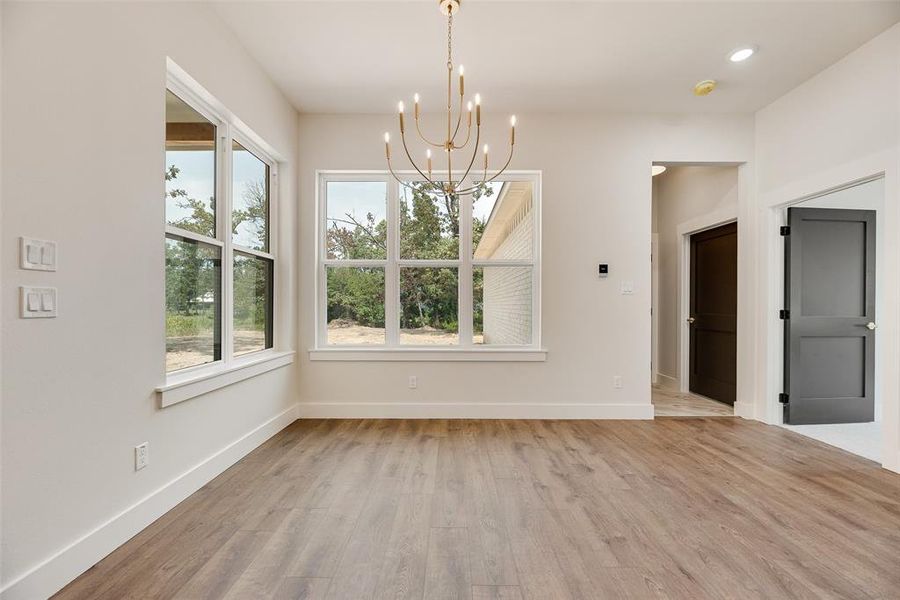 Unfurnished dining area featuring light wood-style flooring, a chandelier, and recessed lighting