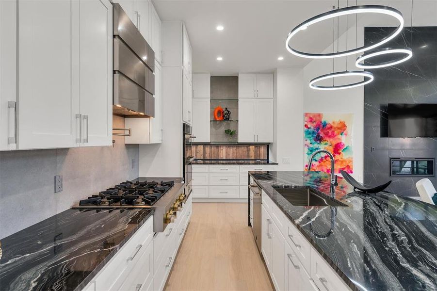 Kitchen featuring sink, white cabinetry, dark stone countertops, light wood-type flooring, and gas stovetop