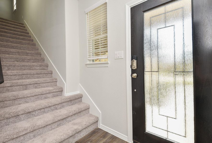 This is the warm, inviting front entrance from the inside; with cool walls, wood-look tile? vinyl flooring? with the grand carpeted staircase easily accessing the 2nd level. This is the warm, inviting front entrance from the inside; with cool walls, wood-look tile? vinyl flooring? with the grand carpeted staircase easily accessing the 2nd level.