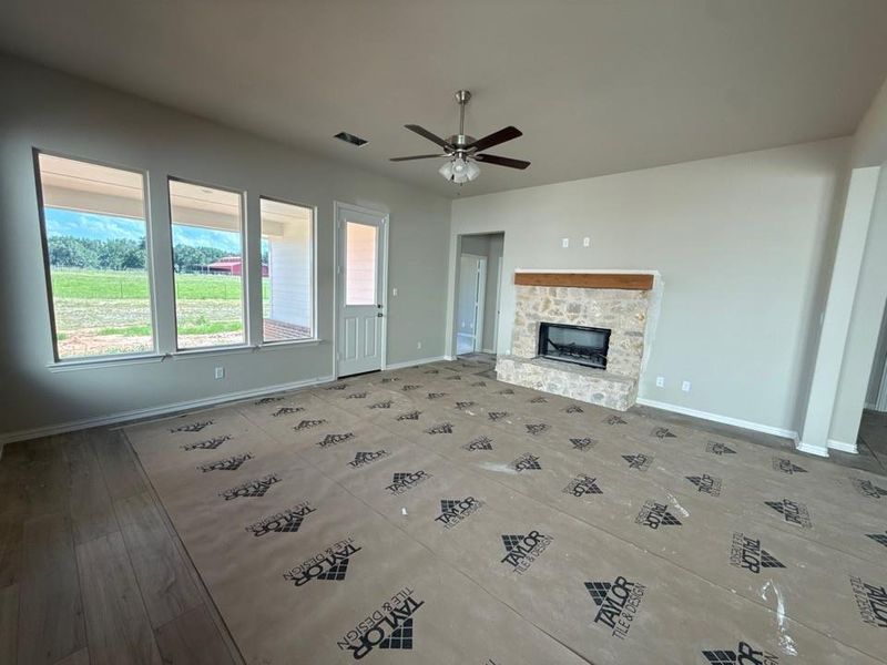 Spacious living area featuring a floor-to-ceiling stone fireplace with a wood mantel Spacious living area featuring a floor-to-ceiling stone fireplace with a wood mantel