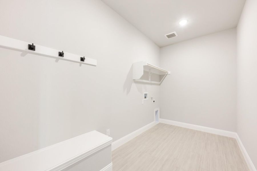 Mudroom with white bench, wall hooks, and upper shelf on light wood-look floors Mudroom with white bench, wall hooks, and upper shelf on light wood-look floors