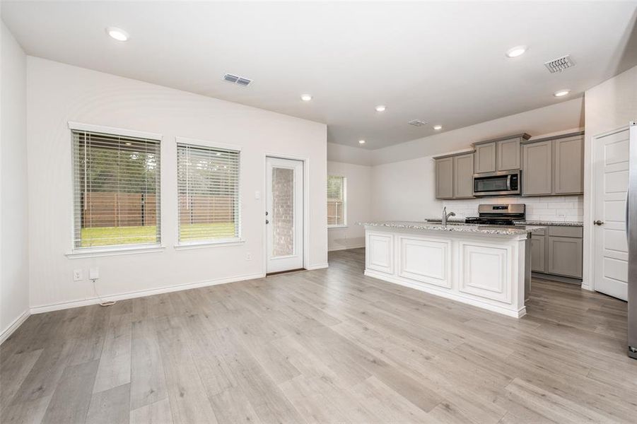 Kitchen featuring gray cabinetry, a kitchen island with sink, tasteful backsplash, recessed lighting, and stainless steel appliances