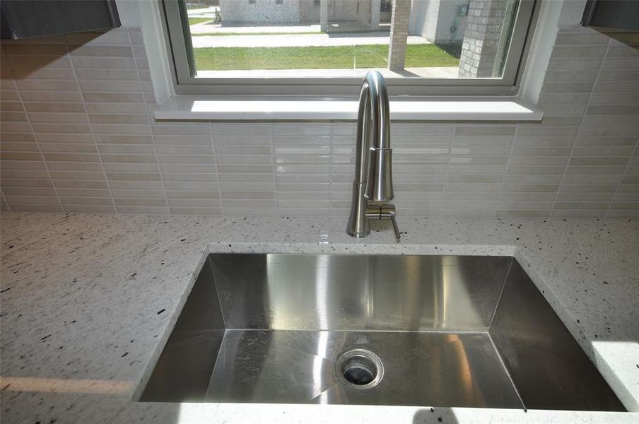 Large single bowl undercounted sink with a window above.