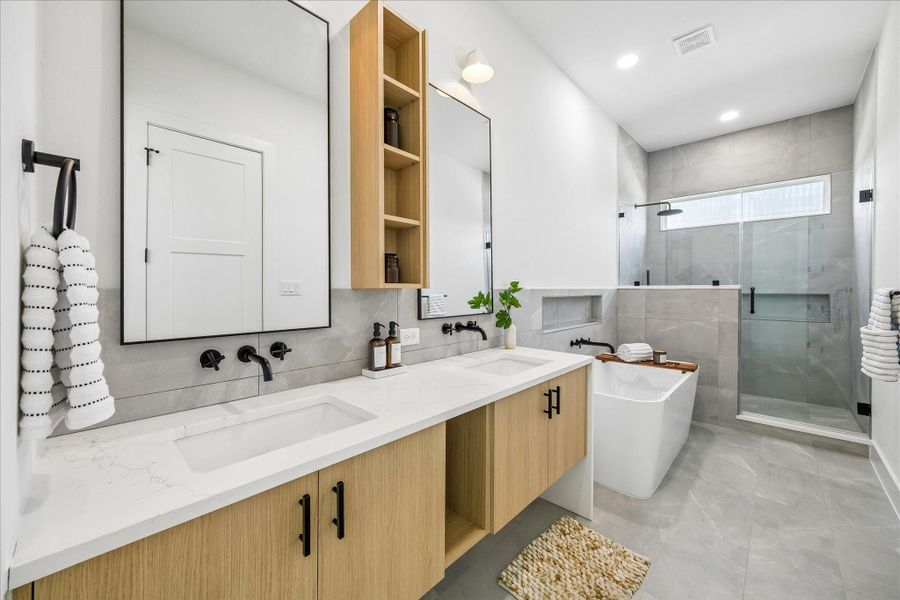 A spa inspired primary bath delivers luxury at every turn. Dual vanities with quartz countertops, warm wood cabinetry, and oversized framed mirrors provide abundant space for busy mornings, while the freestanding soaking tub creates a striking focal point.