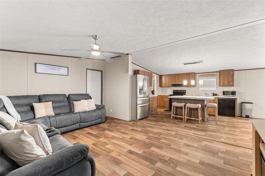 Living room with light wood-type flooring, ceiling fan, and a decorative wall