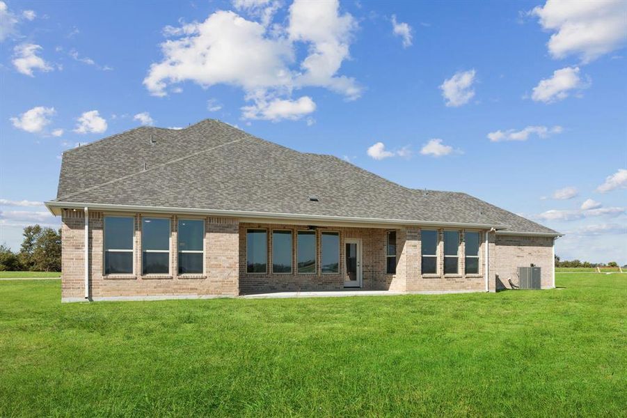 Rear view of house featuring a lawn, a patio area, and brick siding