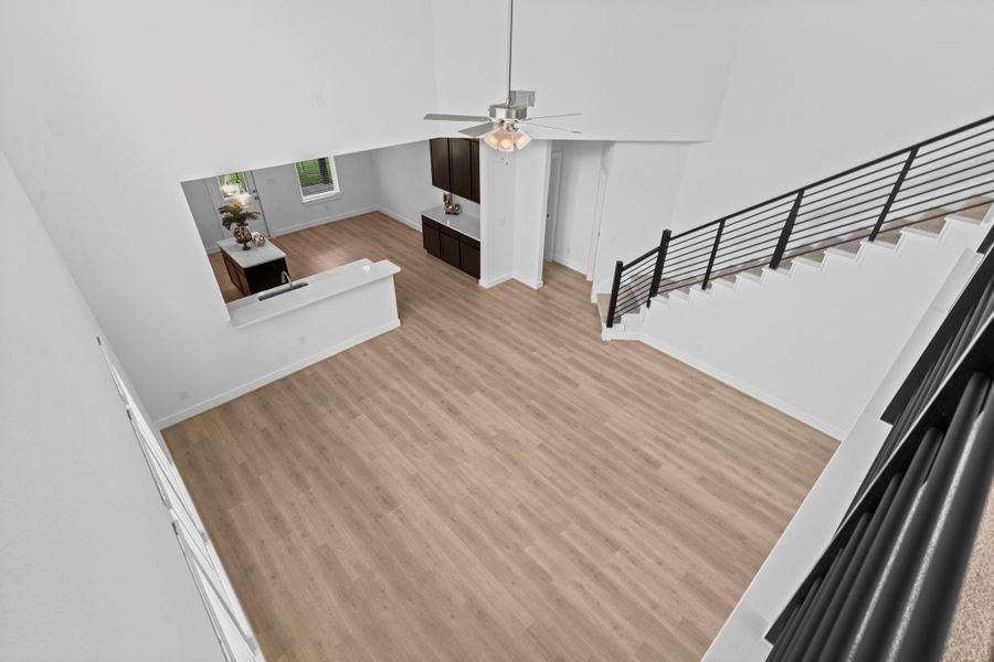 Stunning bird’s-eye view from the upstairs game room reveals the grand living area below, complete with soaring ceilings, modern railing, and beautiful woodlike vinyl plank flooring—highlighting the home’s open-concept elegance. **Image Representative of Plan Only and May Vary as Built**.