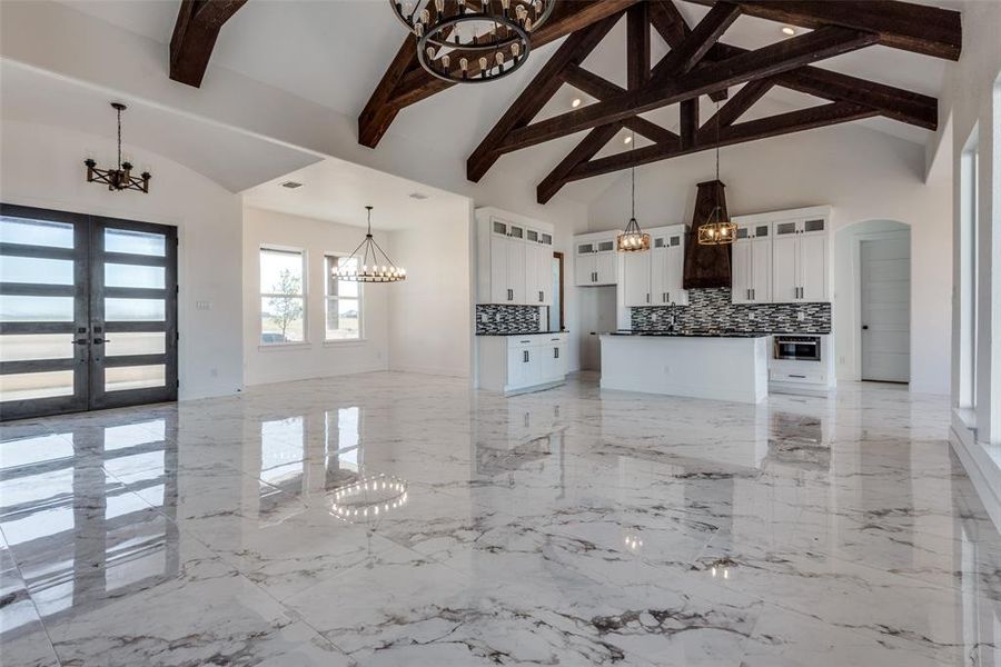 Kitchen featuring decorative backsplash, beam ceiling, white cabinetry, pendant lighting, and french doors