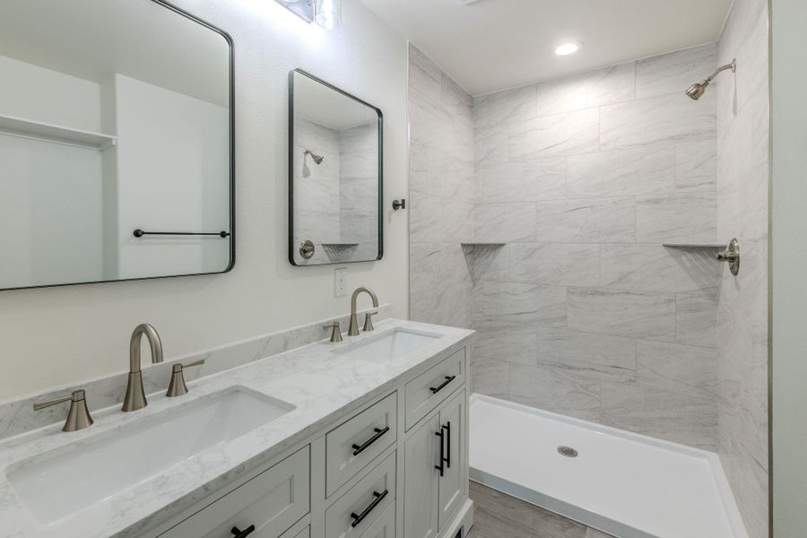 A well-appointed primary bath features a dual vanity with marble countertops and a spacious walk-in shower. A well-appointed primary bath features a dual vanity with marble countertops and a spacious walk-in shower.