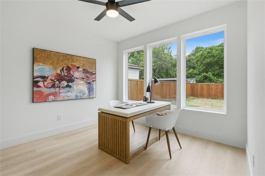 Bright interior space featuring light wood-finish flooring, white walls, and a modern ceiling fan Bright interior space featuring light wood-finish flooring, white walls, and a modern ceiling fan