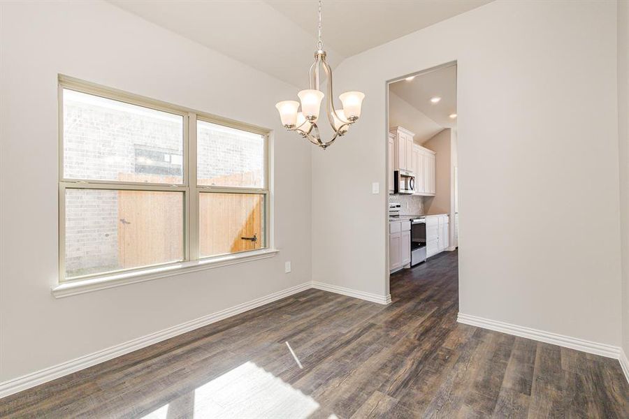 Unfurnished dining area featuring an inviting chandelier and dark wood-type flooring