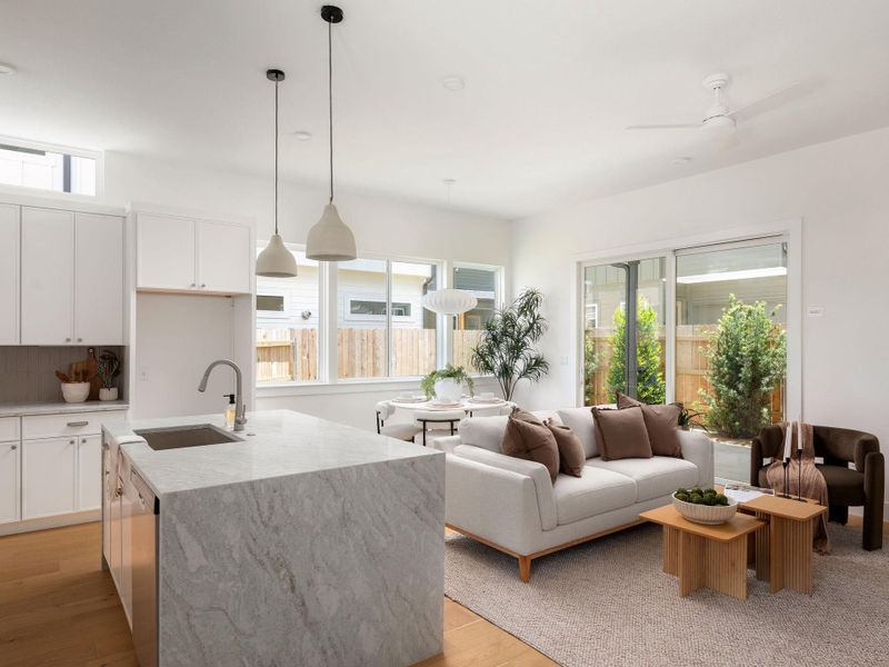 An open concept living area features a grand kitchen island and large windows overlooking the private yard.