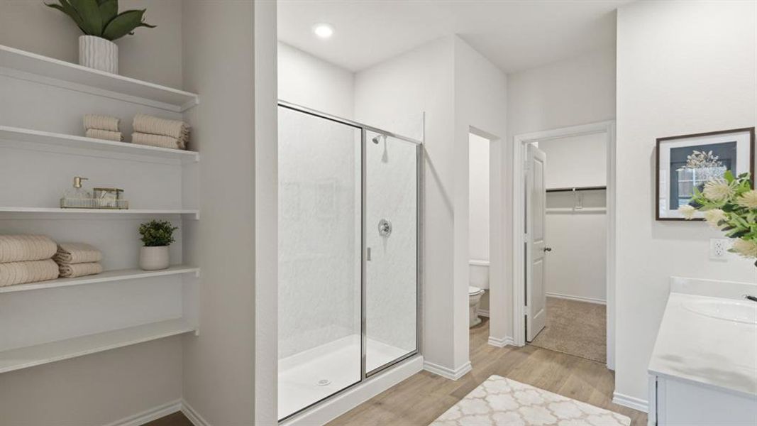 Bathroom featuring a walk in closet, vanity, a stall shower, light wood finished floors, and recessed lighting