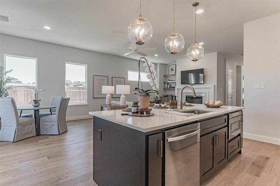 Kitchen featuring stainless steel appliances, a center island with sink, ceiling fan, and light hardwood / wood-style flooring