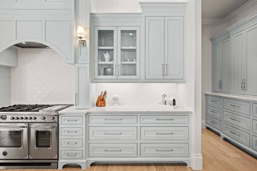 Kitchen with double oven range, light countertops, tasteful backsplash, glass insert cabinets, and crown molding Kitchen with double oven range, light countertops, tasteful backsplash, glass insert cabinets, and crown molding