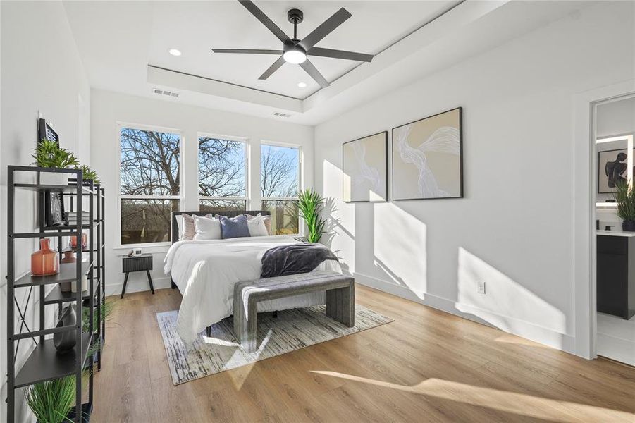 Bedroom with light wood-type flooring, a raised ceiling, ceiling fan, and recessed lighting