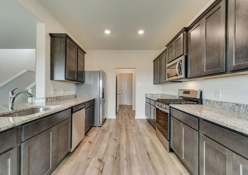 The kitchen has sprawling granite countertops, brown cabinetry and stainless steel appliances.