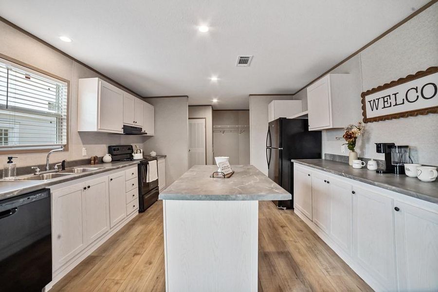 Kitchen with black appliances, a kitchen island, recessed lighting, and white cabinets Kitchen with black appliances, a kitchen island, recessed lighting, and white cabinets