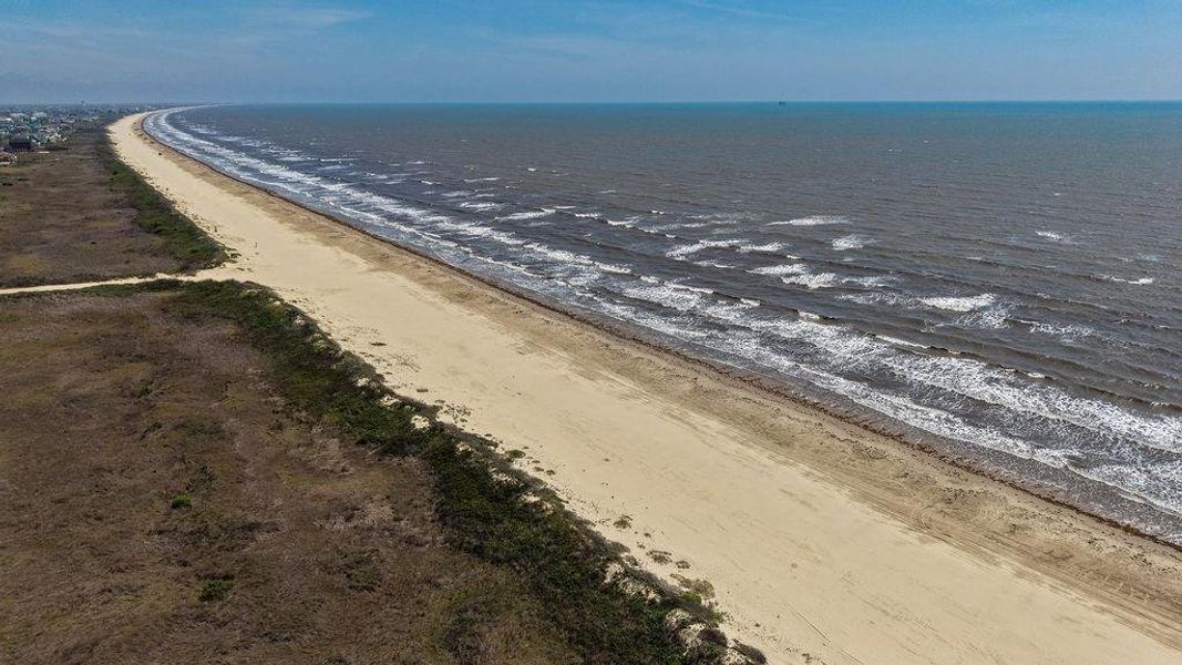 This photo showcases a serene, expansive beach with gentle waves and a sandy shoreline, perfect for those seeking a coastal lifestyle. The area offers natural beauty and a tranquil environment, ideal for a beachside home.