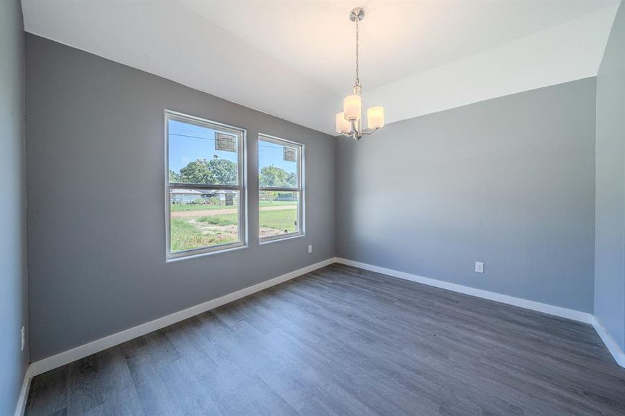 Spare room with dark wood-style floors, a chandelier, and vaulted ceiling Spare room with dark wood-style floors, a chandelier, and vaulted ceiling