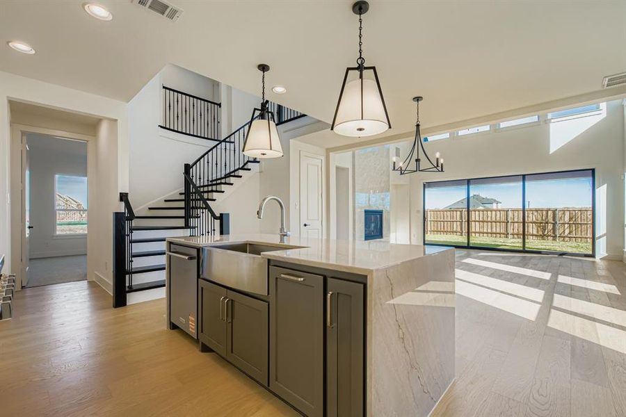 Kitchen featuring light wood finished floors, hanging light fixtures, light stone counters, recessed lighting, and an island with sink Kitchen featuring light wood finished floors, hanging light fixtures, light stone counters, recessed lighting, and an island with sink