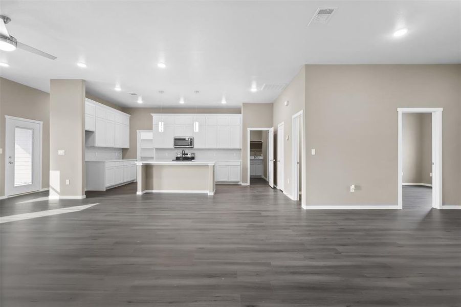 Unfurnished living room featuring dark wood-type flooring and ceiling fan