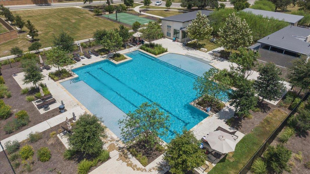 An aerial view showcases a large community swimming pool flanked by pristine stone decking.