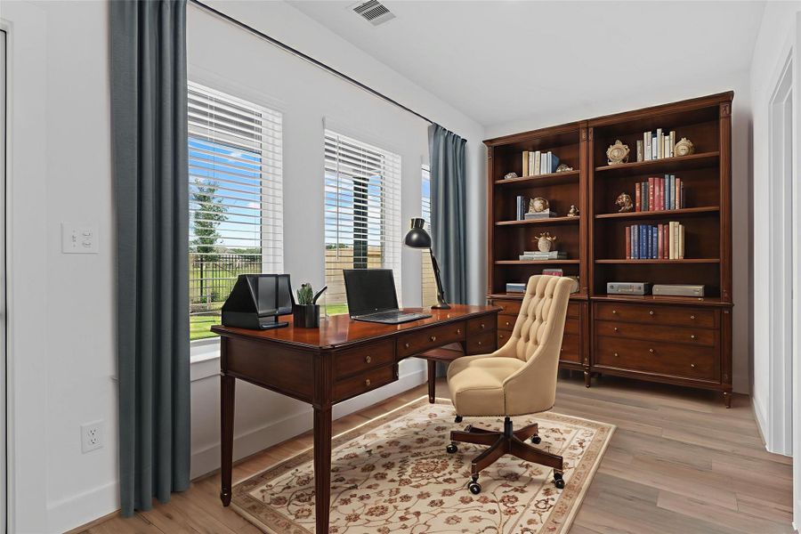 Private home office located at the rear of the home features large windows with scenic lake views, wood look vinyl flooring, and a quiet atmosphere—perfect for remote work or study. *Virtually Staged* **Image Representative of Plan Only and May Vary as Built**.