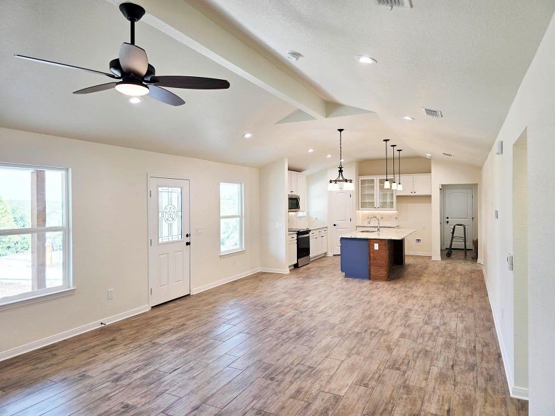 Kitchen with glass insert cabinets, white cabinetry, open floor plan, an island with sink, and hanging light fixtures