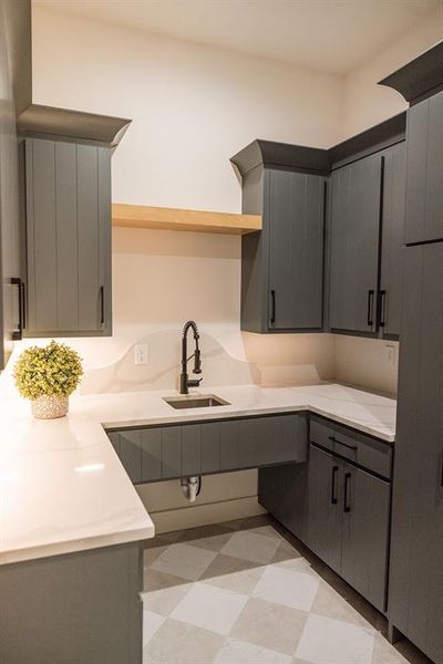 Kitchen featuring open shelves, gray cabinets, light flooring, and light stone counters Kitchen featuring open shelves, gray cabinets, light flooring, and light stone counters