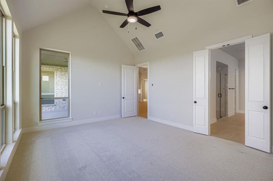 Unfurnished bedroom with light carpet, high vaulted ceiling, and ceiling fan Unfurnished bedroom with light carpet, high vaulted ceiling, and ceiling fan