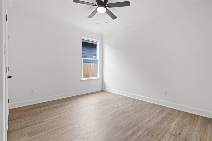 Spare room with light wood-type flooring, ceiling fan, and crown molding