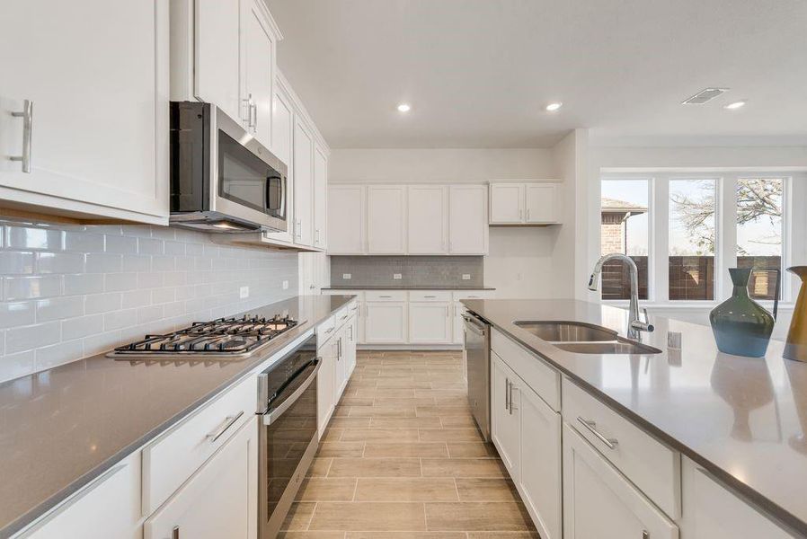 Kitchen with stainless steel appliances, white cabinetry, decorative backsplash, recessed lighting, and light wood-type flooring