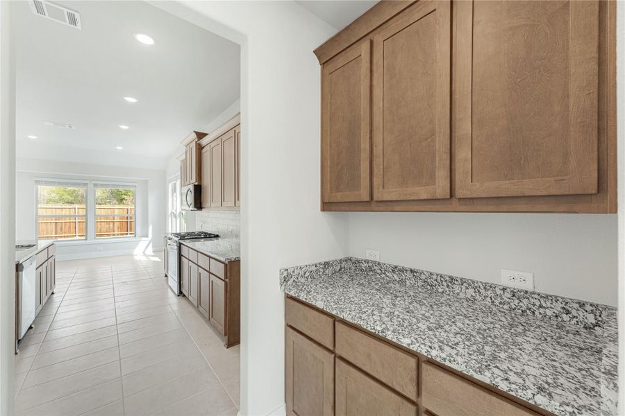 Kitchen with medium wood cabinets, granite countertops, tile floors, and stainless steel appliances