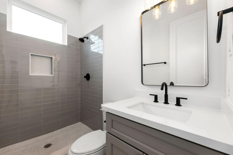 The secondary bathroom offers a refined, contemporary design with elegant light countertops and sleek, modern grey cabinetry. The oversized walk-in shower boasts a stunning custom tile surround, complemented by a decorative mirror that adds a touch of sophistication. With stylish tile floors, chic fixtures, and polished finishes throughout, this space is not only functional but also an inviting retreat. The secondary bathroom offers a refined, contemporary design with elegant light countertops and sleek, modern grey cabinetry. The oversized walk-in shower boasts a stunning custom tile surround, complemented by a decorative mirror that adds a touch of sophistication. With stylish tile floors, chic fixtures, and polished finishes throughout, this space is not only functional but also an inviting retreat.