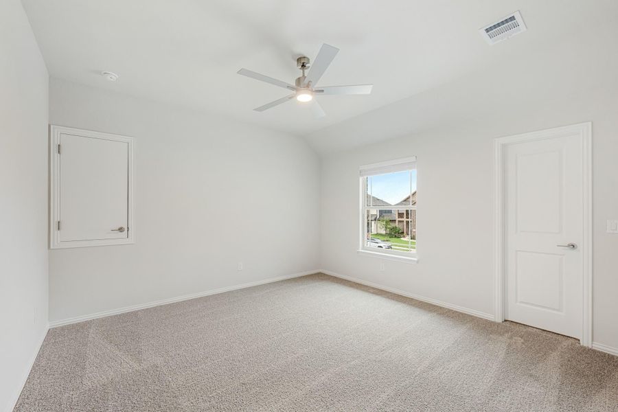 Empty bedroom with vaulted ceiling, ceiling fan, carpet flooring, and a window with natural light Empty bedroom with vaulted ceiling, ceiling fan, carpet flooring, and a window with natural light