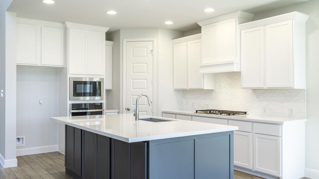 Kitchen with white cabinets, appliances with stainless steel finishes, wood finished floors, a sink, and backsplash Kitchen with white cabinets, appliances with stainless steel finishes, wood finished floors, a sink, and backsplash