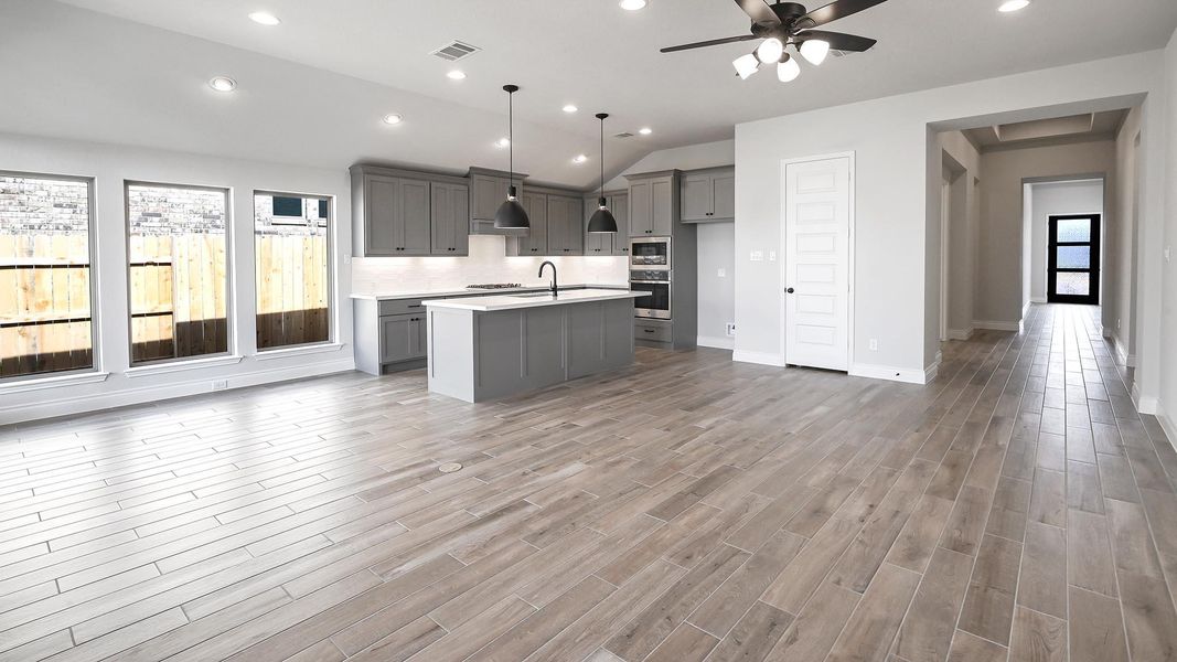 Kitchen with light countertops, visible vents, ceiling fan, a kitchen island with sink, and gray cabinetry Kitchen with light countertops, visible vents, ceiling fan, a kitchen island with sink, and gray cabinetry