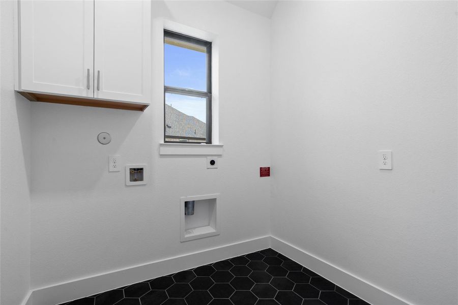 This bright and functional laundry room is conveniently located and ready for your appliances. It features clean white walls, trim, window, and a convenient cabinet for storing your laundry supplies. The tile work in this laundry room is a nice feature!