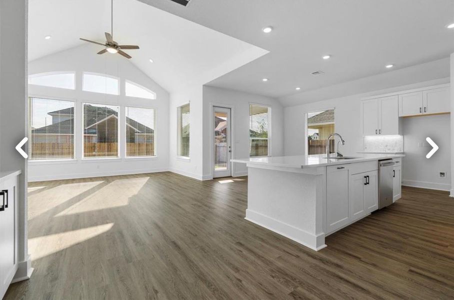 Kitchen featuring white cabinets, a kitchen island with sink, vaulted ceiling, open floor plan, and recessed lighting