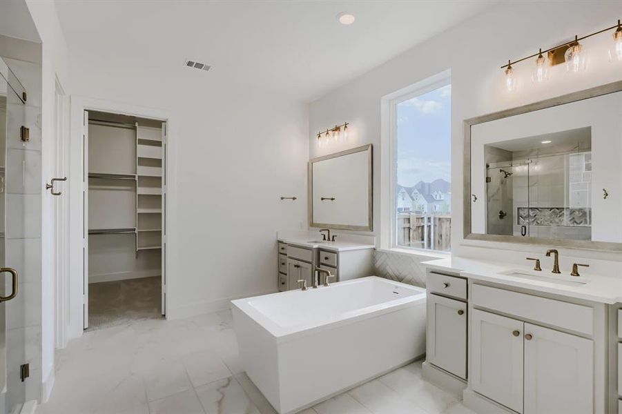 Bathroom featuring a freestanding soaking tub, dual vanities with integrated sinks, and a separate glass-enclosed shower Bathroom featuring a freestanding soaking tub, dual vanities with integrated sinks, and a separate glass-enclosed shower