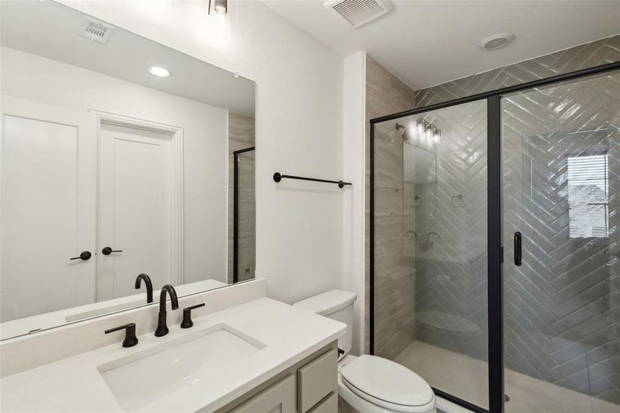 Bathroom with vanity, toilet, and a shower with shower door