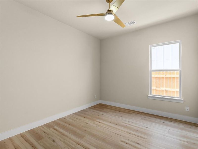 Room with light beige walls, wood-finish flooring, a contemporary gold-tone ceiling fan with integrated lighting, and a double-hung window