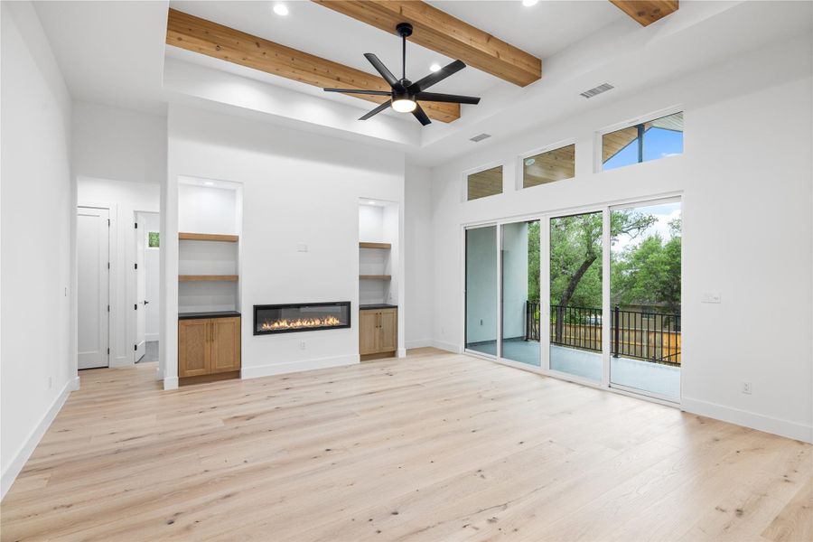 Living room with engineered white oak flooring, beamed ceiling and electric glass covered fireplace. Living room with engineered white oak flooring, beamed ceiling and electric glass covered fireplace.