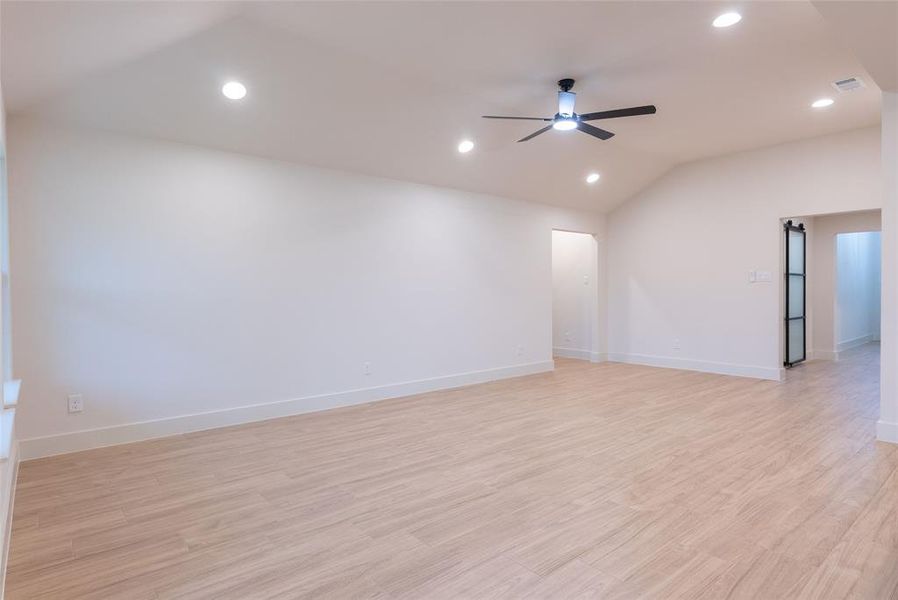 Empty room with vaulted ceiling, light wood finished floors, recessed lighting, and ceiling fan