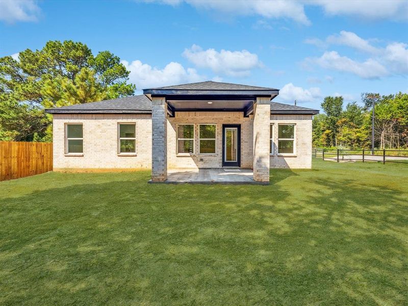 Back of house with a fenced backyard, a patio area, brick siding, and roof with shingles