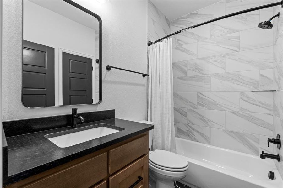 Bathroom with shower / bath combo with shower curtain, vanity, and a textured wall Bathroom with shower / bath combo with shower curtain, vanity, and a textured wall